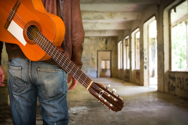 uomo con la chitarra in un edificio in stile urbano in rovina