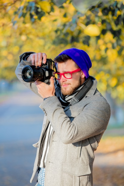 Uomo con la macchina fotografica al vicolo di stagione autunnale