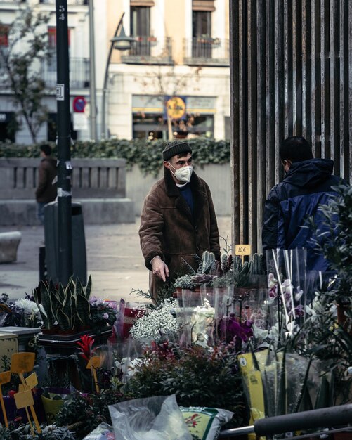 Uomo con la maschera in piedi vicino al negozio di fiori