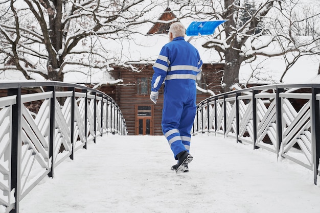 Uomo con la pala da neve sulla vista posteriore della spalla.