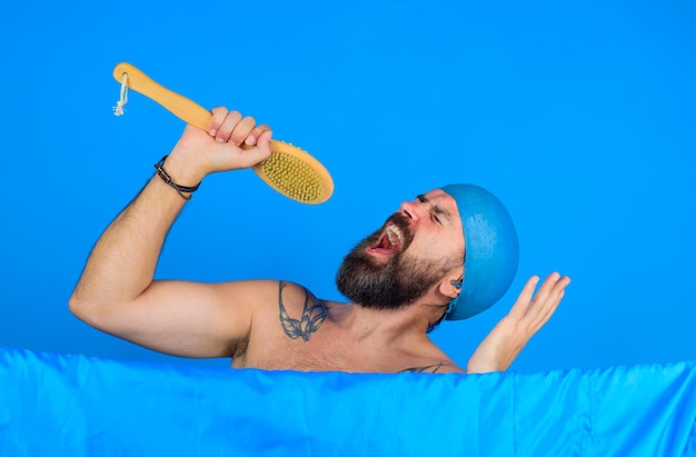 Uomo con la spazzola da bagno uomo che fa la doccia uomo in bagno che lava il corpo uomo barbuto che lava i capelli