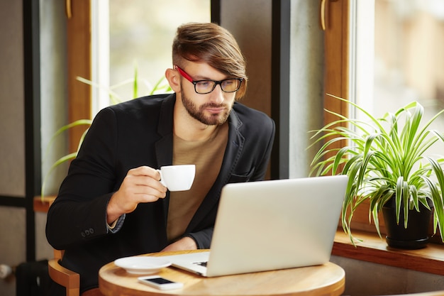 Uomo con la tazza al computer portatile