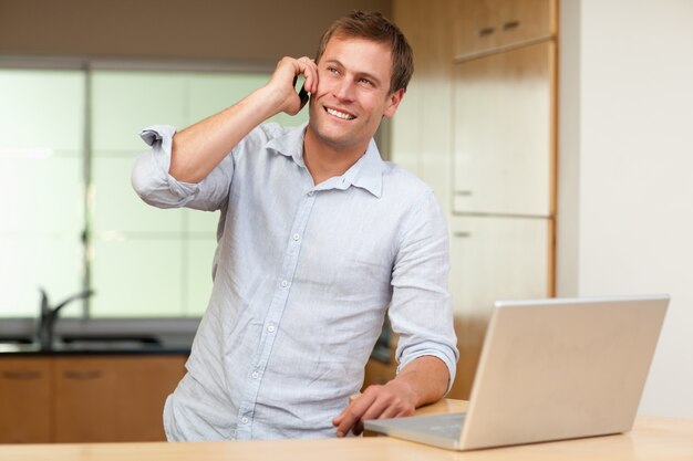 Uomo con laptop e cellulare in cucina