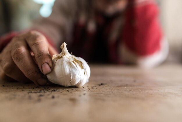 Uomo con le mani sporche che tengono un bulbo di aglio fresco