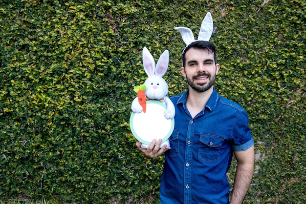 Uomo con le orecchie del coniglietto di pasqua che tiene il coniglietto di pasqua