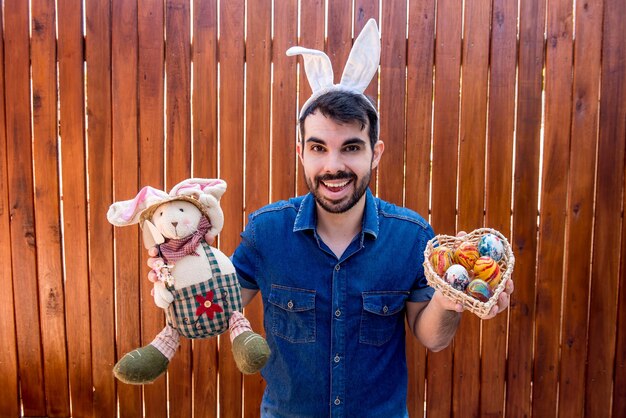 Uomo con le orecchie di coniglio che tengono le uova e il fuoco selettivo del coniglietto di pasqua