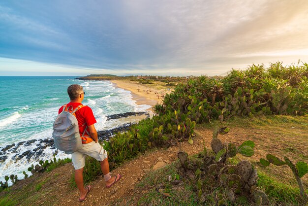 Uomo con lo zaino che esamina costa tropicale dalla scogliera qui sopra. Destinazione di viaggio in Vietnam, provincia di Phu Yen tra Da Nang e Nha Trang. Bai Xep splendida spiaggia di sabbia