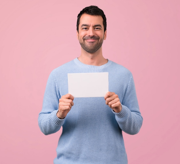 Uomo con maglione blu che tiene un cartello bianco vuoto