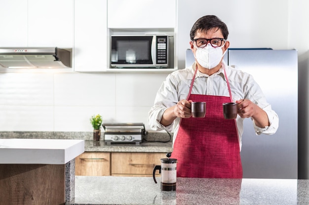 Uomo con maschera che consegna due tazze di caffè al bancone della cucina di una caffetteria accanto a una stampa francese