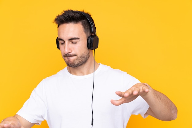 Uomo con musica d'ascolto della barba sopra la parete isolata