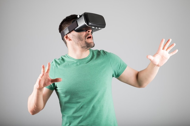 Uomo con occhiali per realtà virtuale che mostra gesto isolato su uno sfondo grigio