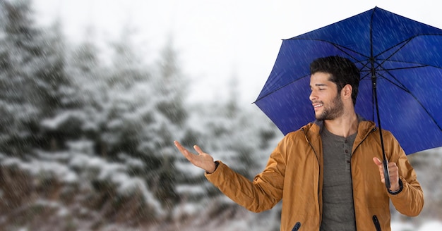 Uomo con ombrello blu nella foresta di neve