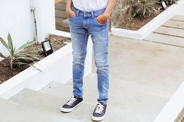 Uomo con pantaloni in denim blu e scarpe da ginnastica in piedi