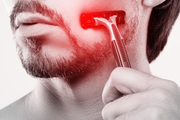 Uomo con pelle sensibile durante la routine di rasatura con un rasoio di sicurezza