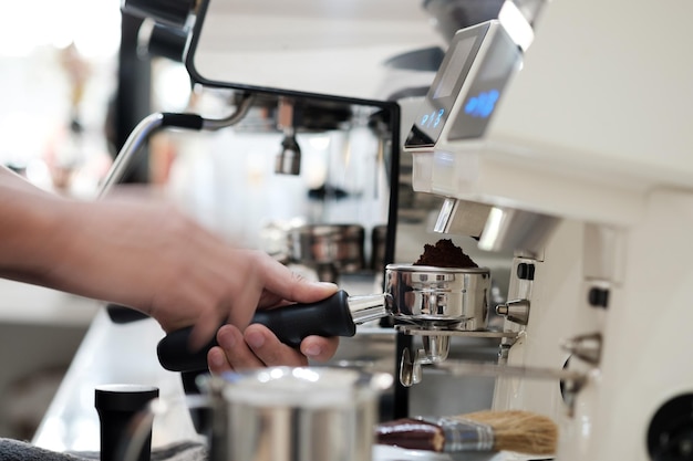 Uomo con portafiltro caricato con caffè macinato e preparazione di caffè espresso fresco