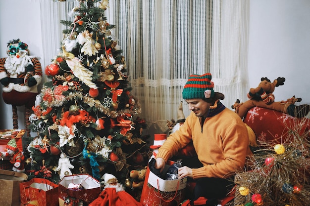 Uomo con regali vicino all'albero di Natale