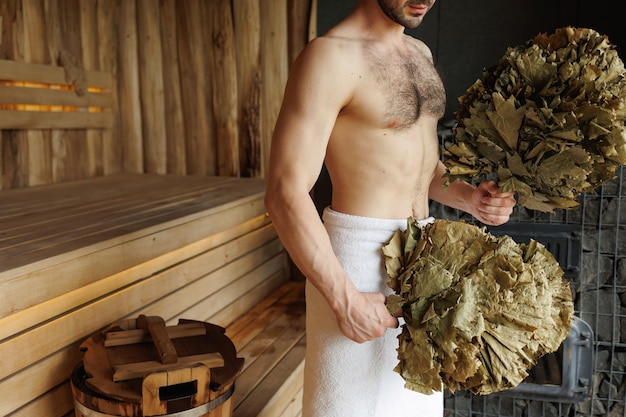 Uomo con scopa foglia in sauna