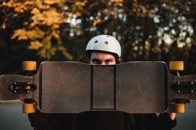 Uomo con skate, longboard al tramonto. Foto di alta qualità