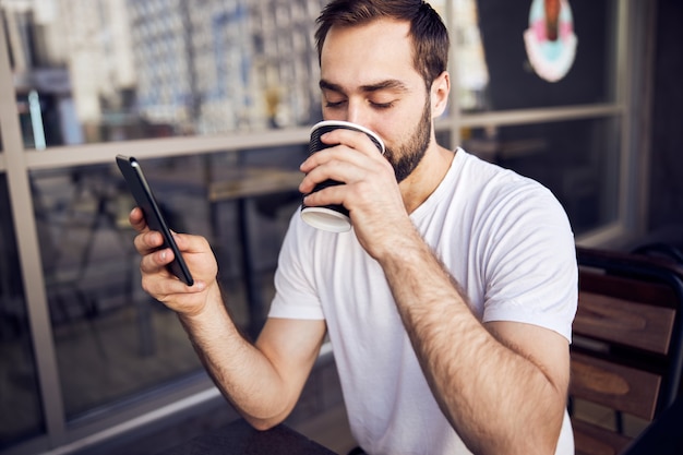 Uomo con smartphone e caffè