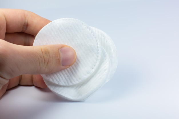 Uomo con spugne di cotone bianco su sfondo bianco. Foto ravvicinata. Procedure di bellezza, medicina e cosmetici.