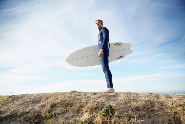 uomo con tavola da surf sulla spiaggia