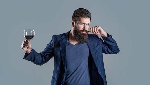 Uomo con un bicchiere di vino rosso nelle sue mani Degustatore sommelier con bicchiere di vino cantina enologo maschio Barba uomo barbuto sommelier degustazione vino rosso