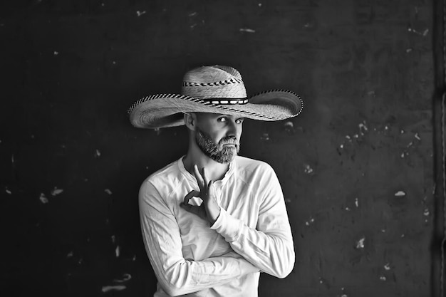 uomo con un cappello di paglia con tesa in studio gesti con le mani e le dita, punti. Stile sambrero dell'America occidentale, Messico