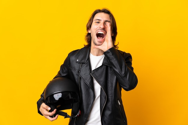 Uomo con un casco da motociclista isolato su sfondo giallo che grida con la bocca spalancata