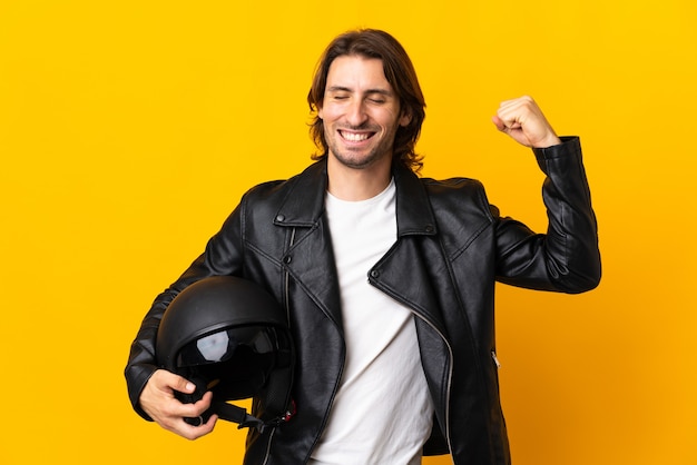 Uomo con un casco da motociclista isolato su sfondo giallo facendo un gesto forte
