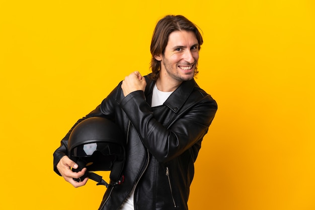 Uomo con un casco da motociclista isolato sulla parete gialla che celebra una vittoria