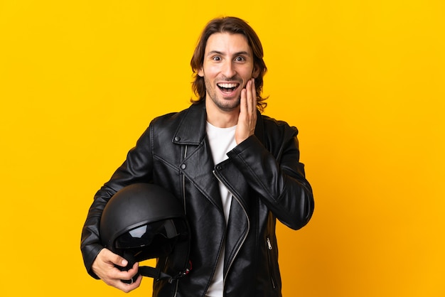 Uomo con un casco da motociclista isolato sulla parete gialla con espressione facciale sorpresa e scioccata