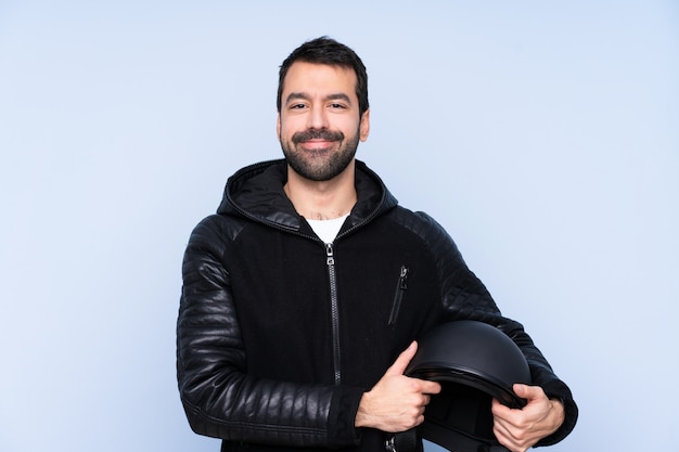 Uomo con un casco da motociclista sul muro isolato mantenendo le braccia incrociate in posizione frontale