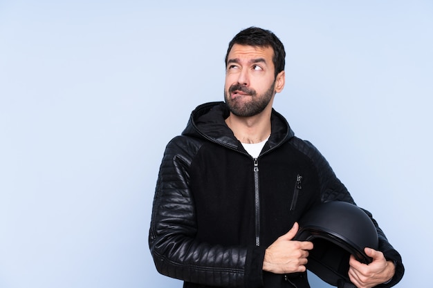 Uomo con un casco del motociclo sopra la parete isolata