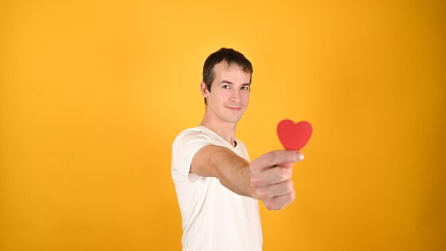 Uomo con un cuore rosso tra le mani su giallo