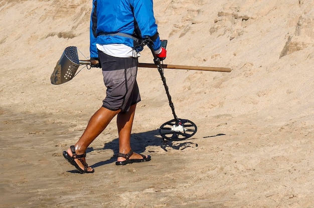 Uomo con un metal detector su una spiaggia sabbiosa del mare