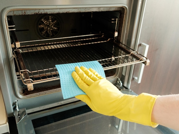 Uomo con un panno che pulisce la stufa della cucina