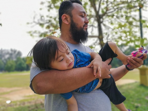 Uomo con una bambina in braccio al parco