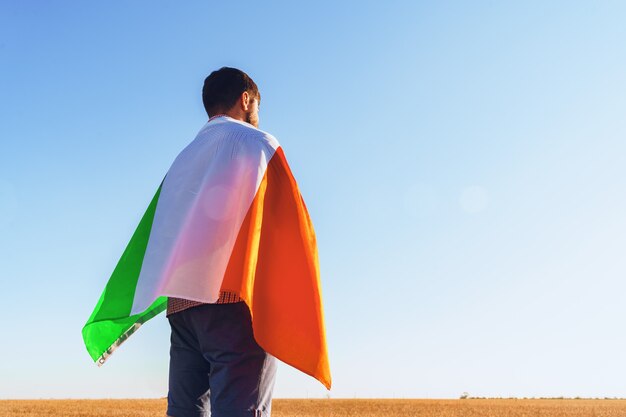 Uomo con una bandiera dell'Italia in piedi in campo