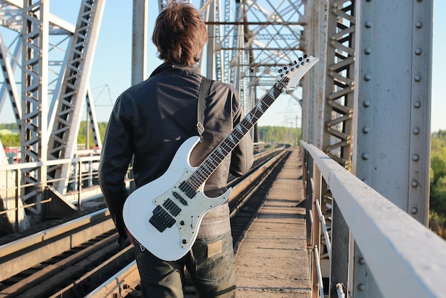 Uomo con una chitarra su una ferrovia