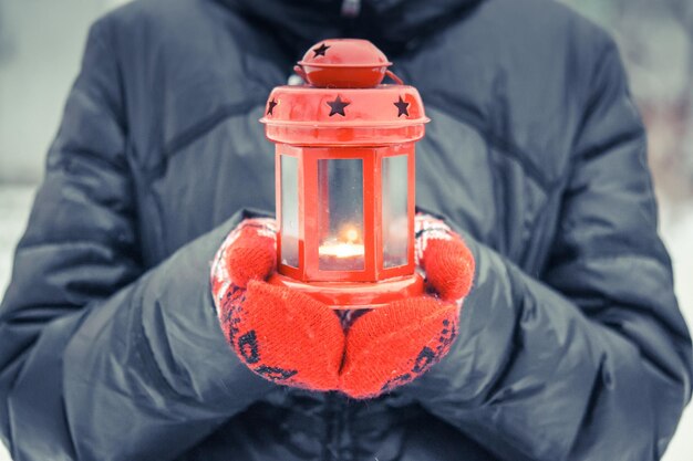 Uomo con una lanterna a candela rossa con una candela vicino un uomo vestito con un cappotto caldo e guanti rossi