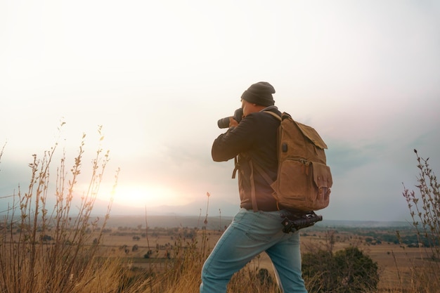 Uomo con una macchina fotografica che scatta foto al tramonto