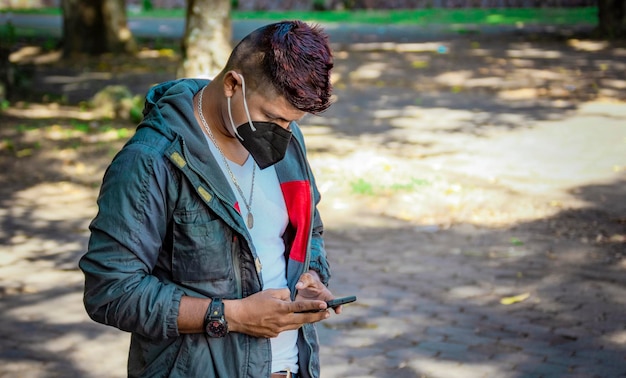 Uomo con una maschera che scrive con il suo telefono giovane con una maschera che scrive con il suo cellulare