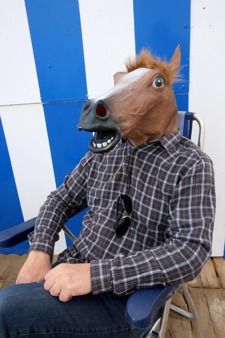 Foto uomo con una maschera da cavallo seduto su una sedia