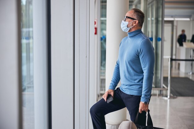 Uomo con una maschera in piedi al terminal dell'aeroporto