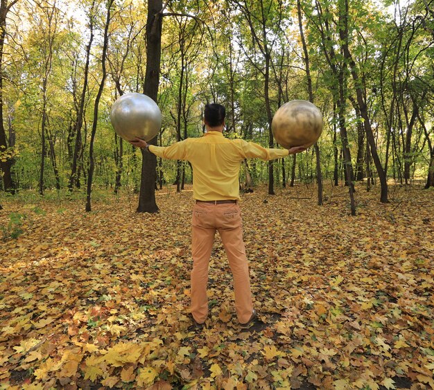 uomo con una strana testa a sfera dorata nella foresta