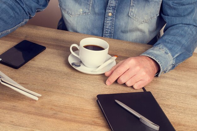 Uomo con una tazza di caffè che lavora alla sua scrivania