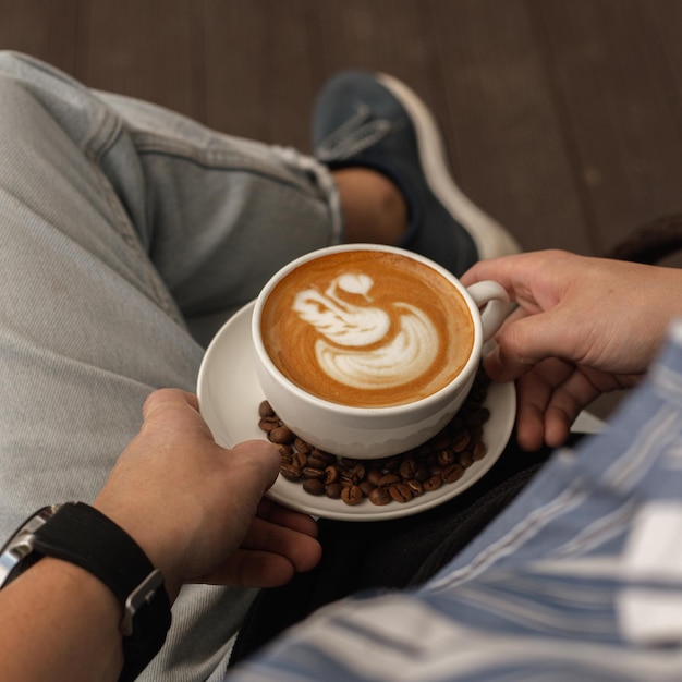 uomo con una tazza di caffè con schiuma di latte art seduto nella caffetteria