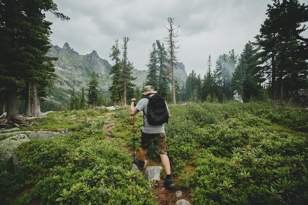 Uomo con uno zaino che cammina attraverso la foresta