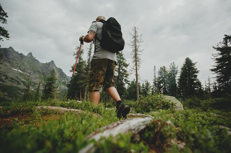 Foto uomo con uno zaino che cammina attraverso la foresta