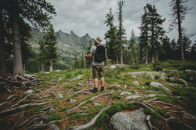 Uomo con uno zaino che cammina attraverso la foresta